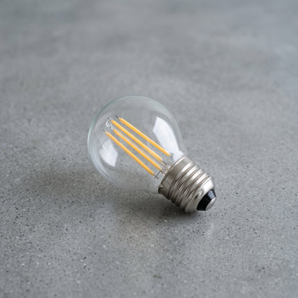 Ampoule LED à filament E27 G45 allongée sur béton gris, filaments dorés, culot nickel