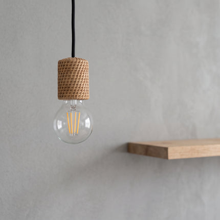Ampoule LED à filament E27 G45 vissée dans une suspension rattan, fond béton gris, étagère chêne