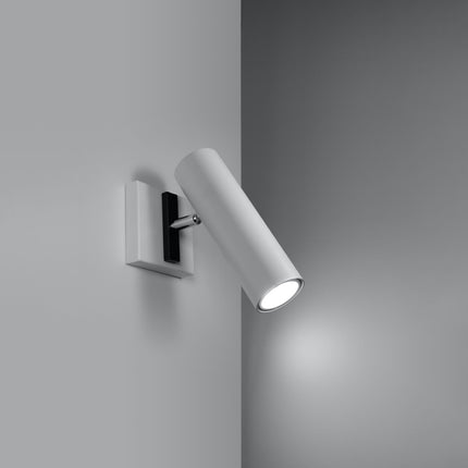 Applique acier orientable blanche allumée dans un angle de mur gris