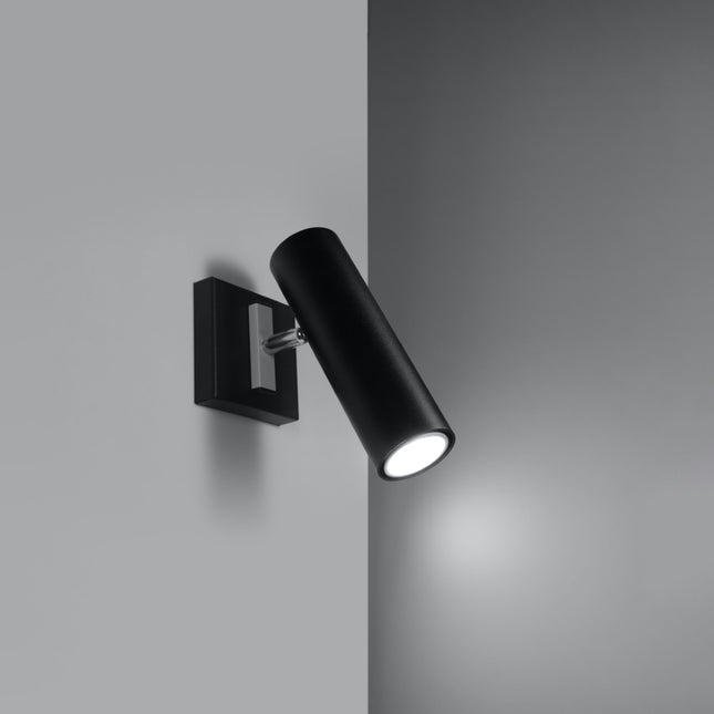 Applique acier orientable noire allumée dans un angle de mur gris