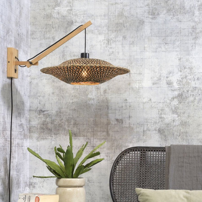 Applique murale Bali en bambou tressé naturel et noir, bras articulé, allumée dans un salon avec plante