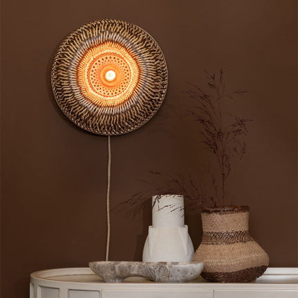 Applique murale Barbados en bambou tressé naturel et brun, allumée au-dessus d'une console avec vases décoratifs