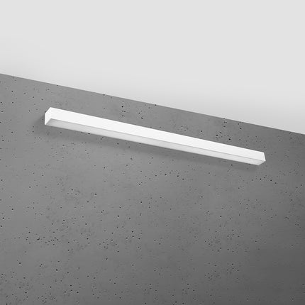 Applique barre moderne LED blanche 118 cm installée sur un mur de béton