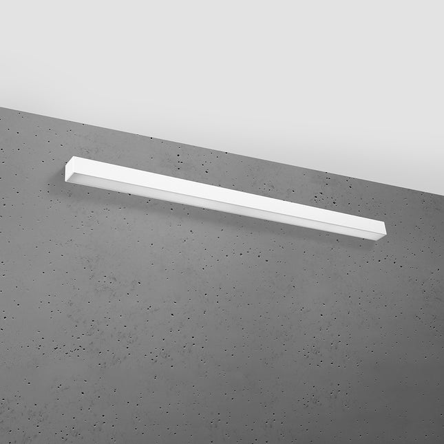 Applique barre moderne LED blanche 118 cm installée sur un mur de béton