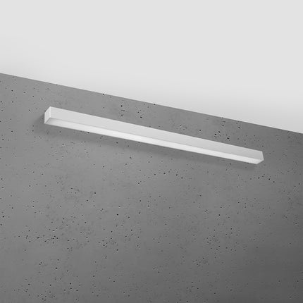 Applique barre moderne LED grise 118 cm installée sur un mur de béton