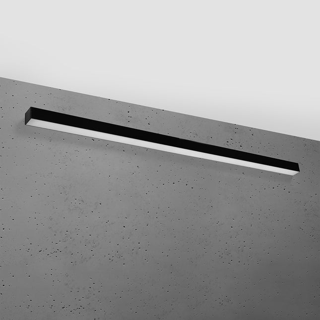 Applique barre moderne LED noire 150 cm installée sur un mur de béton