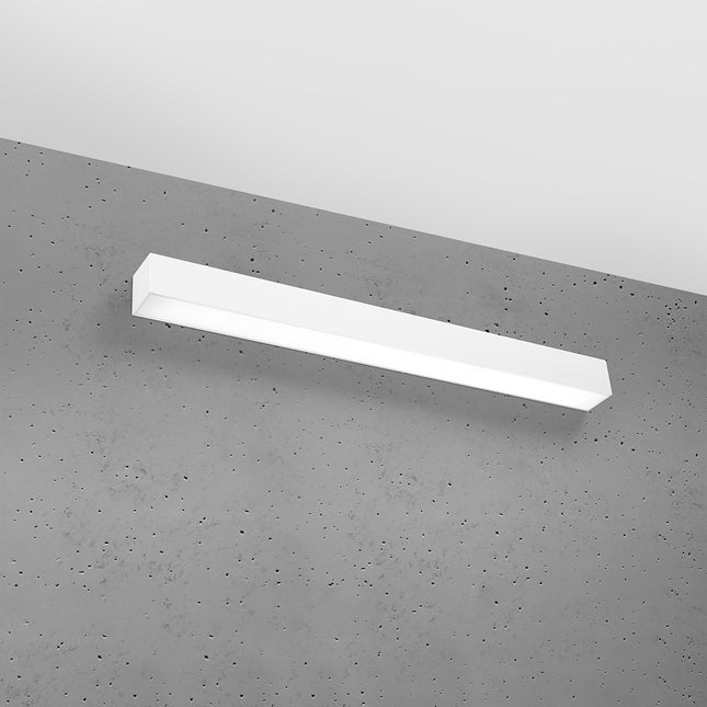 Applique barre moderne LED blanche installée sur un mur de béton