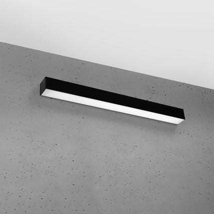 Applique barre moderne LED noire installée sur un mur de béton