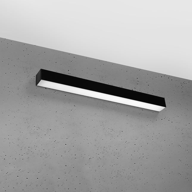 Applique barre moderne LED noire installée sur un mur de béton