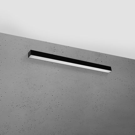 Applique barre moderne LED noire 90 cm installée sur un mur de béton