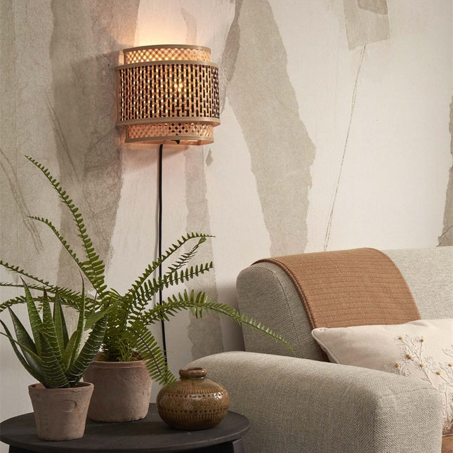 Bhutan black and natural woven bamboo wall light switched on above a sofa in a living room