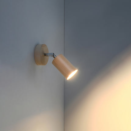 Applique en bois naturel allumée dans un angle de mur clair, faisceau chaud dirigé vers le bas
