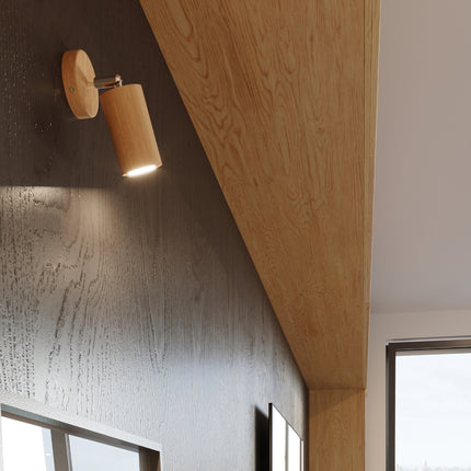 Applique en bois naturel fixée sur un mur en bois foncé, spot allumé éclairant vers le bas