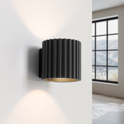 Applique Aura noire diffusant un éclairage haut et bas sur un mur clair