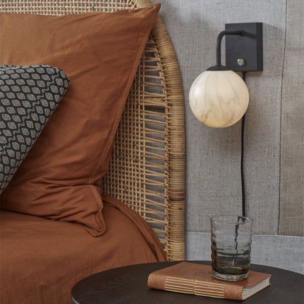 Applique murale Carrara globe marbre et noir installée au-dessus d'une table de chevet