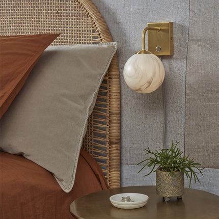 Gros plan du globe en verre effet marbre de l'applique Carrara et du bras en métal doré
