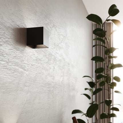 Détail rapproché d'une applique carrée noire LED IP54 allumée au mur