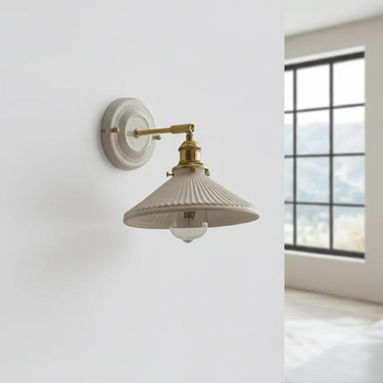 Applique vintage en céramique blanc crème et bras en laiton orientable dans une pièce lumineuse