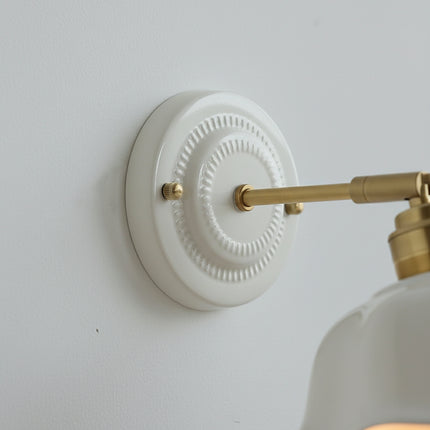 Gros plan de la platine murale en céramique blanche à décor en relief avec bras en laiton