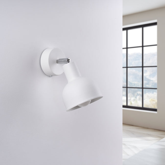 Applique Elba blanche installée au-dessus d'une tête de lit dans une chambre