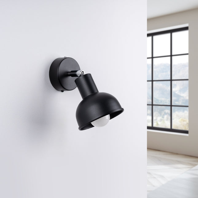 Applique Elba noire installée au-dessus d'une tête de lit dans une chambre
