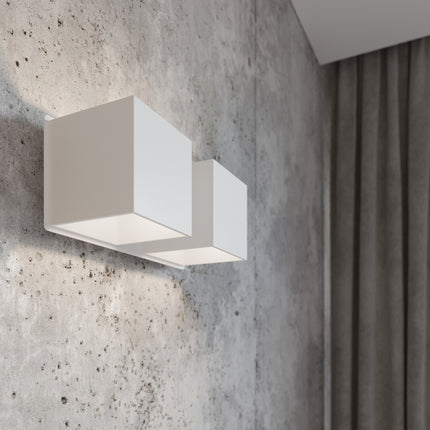 Gros plan de l'applique Cube LED 2 feux blanche allumée, lumière rasante sur mur en béton