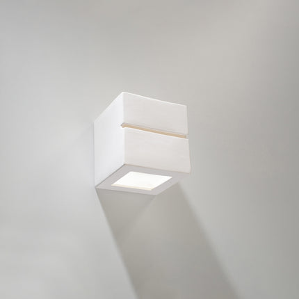 Applique murale Cube Ligne en céramique blanche allumée dans un salon scandinave