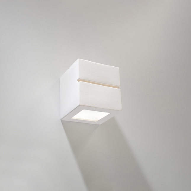 Applique murale Cube Ligne en céramique blanche allumée dans un salon scandinave