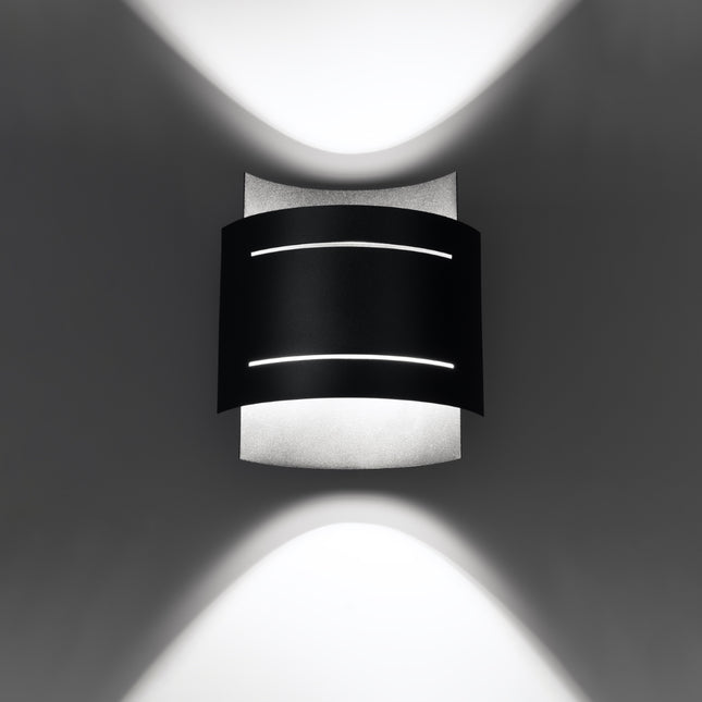 Applique Double Rampe noire allumée, diffusant une lumière douce vers le haut et vers le bas du mur.