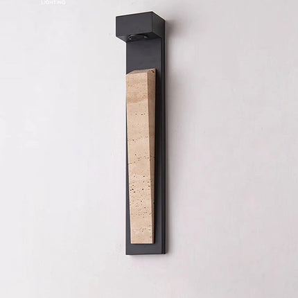 Applique extérieure en pierre naturelle noire créant une ambiance chaleureuse sur un mur de jardin