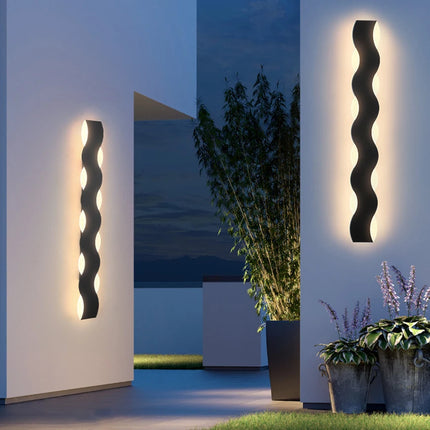 Appliques extérieures LED ondulées éclairant une terrasse et un jardin en soirée