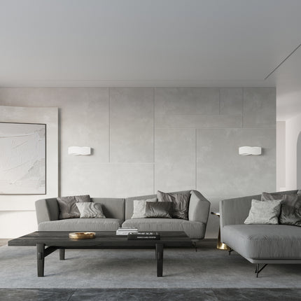 Applique murale Flux Lumineux 40 blanche allumée au-dessus d'un canapé gris, ambiance épurée