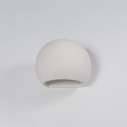 Applique globe en céramique blanche allumée au-dessus d'un lit