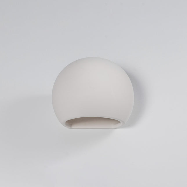 Applique globe en céramique blanche allumée au-dessus d'un lit