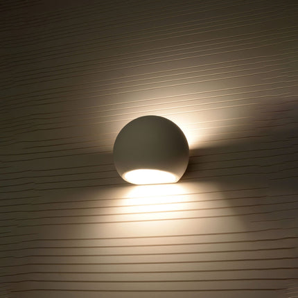 Applique globe céramique diffusant une lumière douce dans un salon