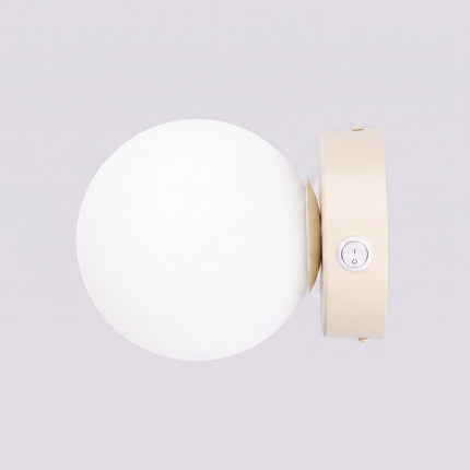 Applique Globe Solis beige sur fond coloré, vue de trois quarts