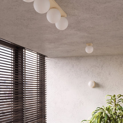 Applique Globe Solis beige dans une pièce claire à stores en bois