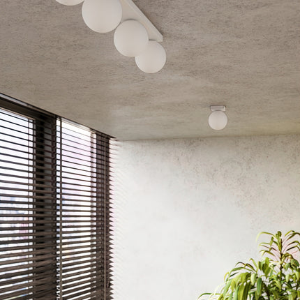 Applique Globe Solis blanc dans une pièce claire à stores en bois