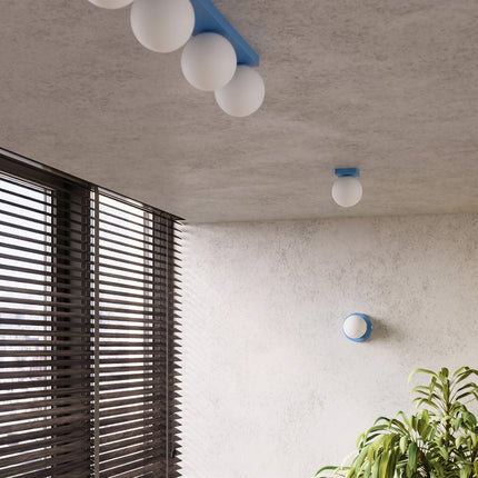 Applique Globe Solis bleu ciel dans une pièce claire à stores en bois