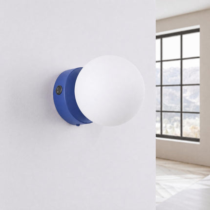 Applique Globe Solis bleu outremer, installée au mur dans un intérieur clair