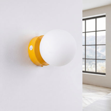 Applique Globe Solis jaune, installée au mur dans un intérieur clair