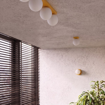 Applique Globe Solis jaune dans une pièce claire à stores en bois