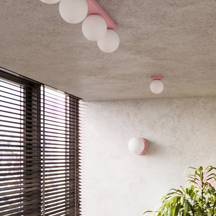 Applique Globe Solis rose dans une pièce claire à stores en bois