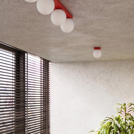 Applique Globe Solis rouge dans une pièce claire à stores en bois