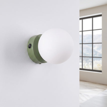 Applique Globe Solis vert olive, installée au mur dans un intérieur clair