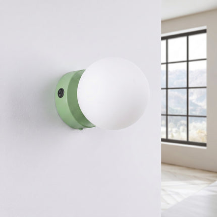 Applique Globe Solis vert sauge, installée au mur dans un intérieur clair