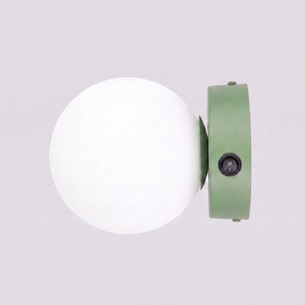Applique Globe Solis vert sauge sur fond coloré, vue de trois quarts