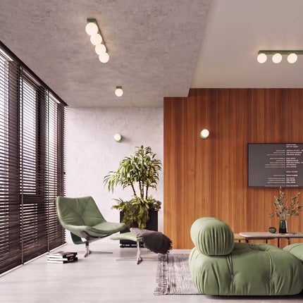 Applique Globe Solis vert sauge dans un salon lumineux aux boiseries claires
