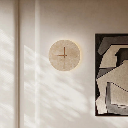 Horloge murale en travertin diffusant un halo chaud dans un couloir baigné de lumière naturelle