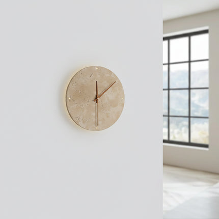 Applique horloge en travertin allumée sur un mur clair, halo lumineux doux et fenêtre en arrière-plan